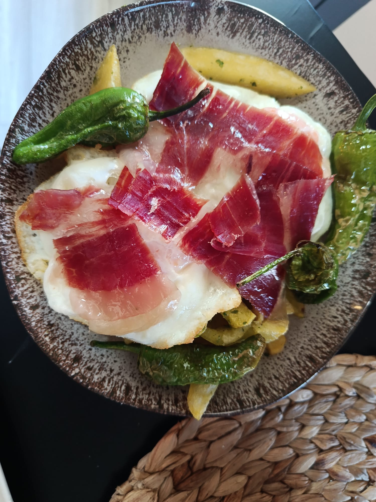 Huevos rotos con jamón ibérico y pimientos de padrón del Bar Sam
